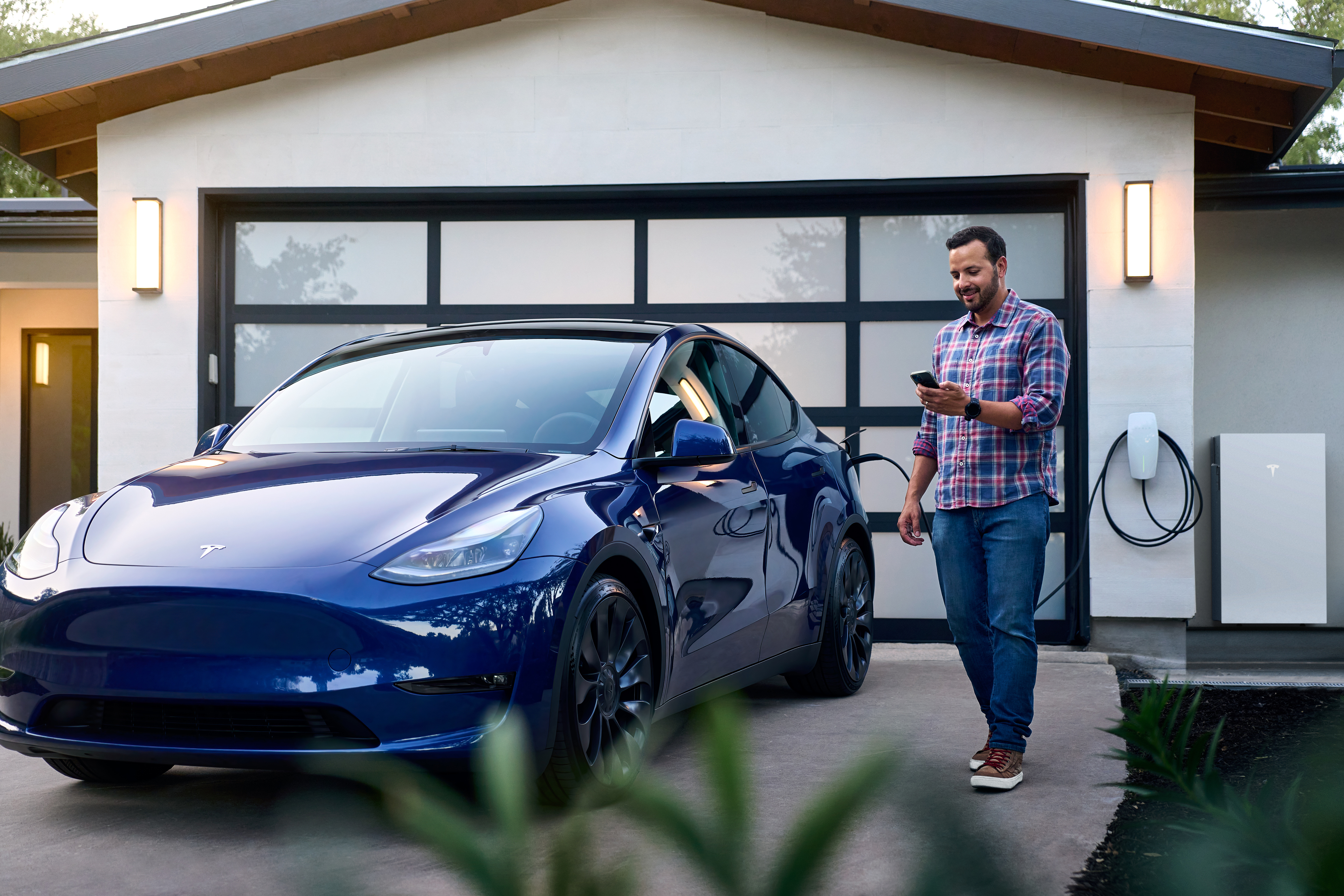 Tesla owner with Model Y and Wall Connector at home
