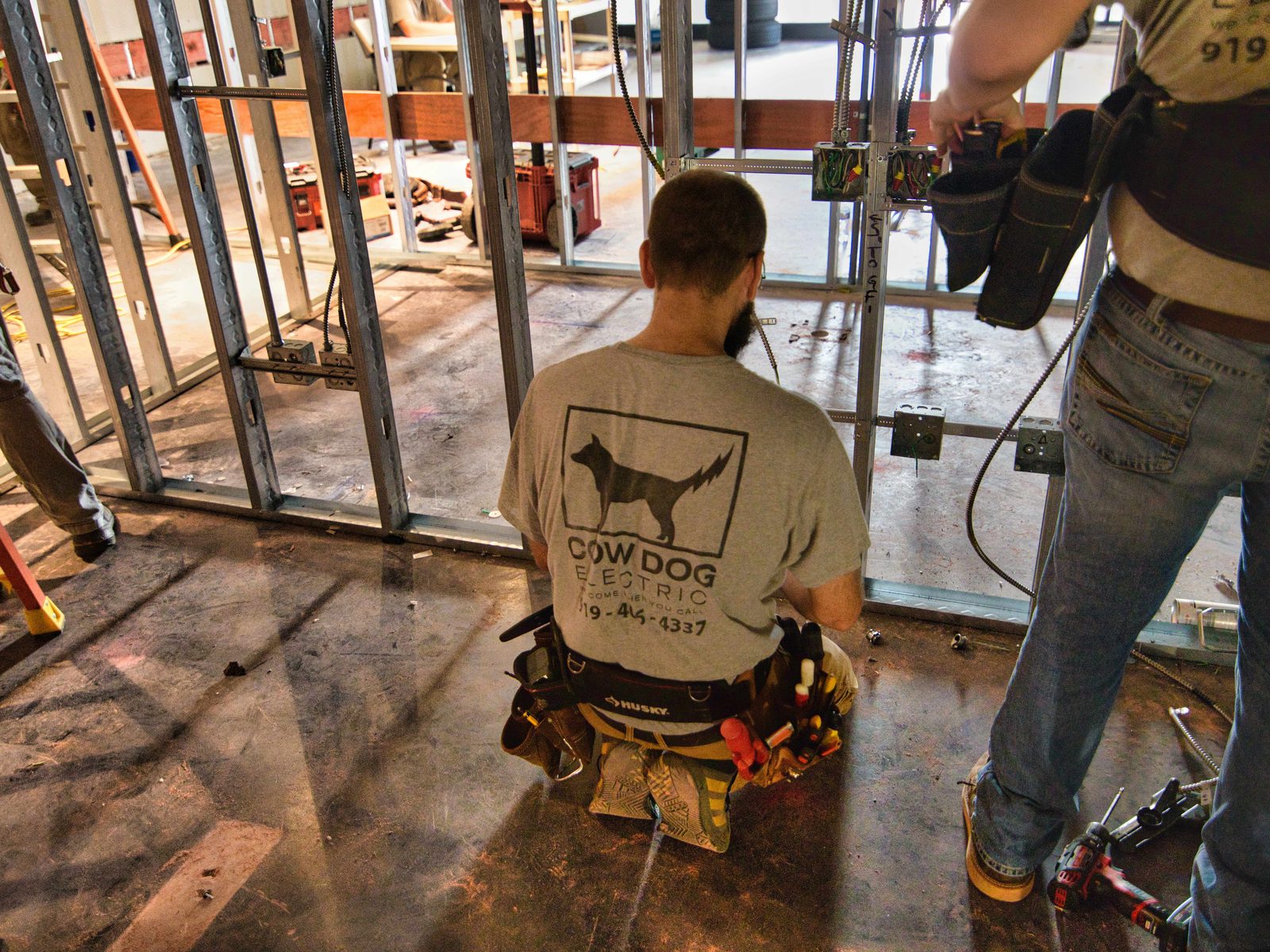 Cow Dog electricians wiring boxes on metal stud framing in a commercial build out